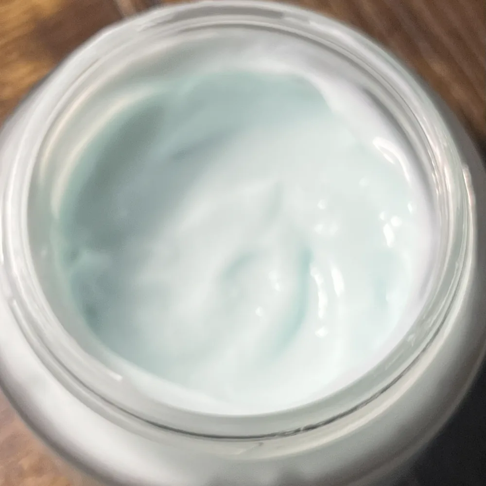 Close view of pale blue cream texture inside an open glass jar