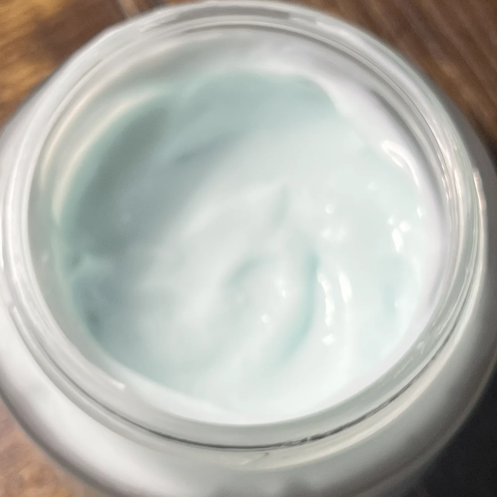 Close view of pale blue cream texture inside an open glass jar