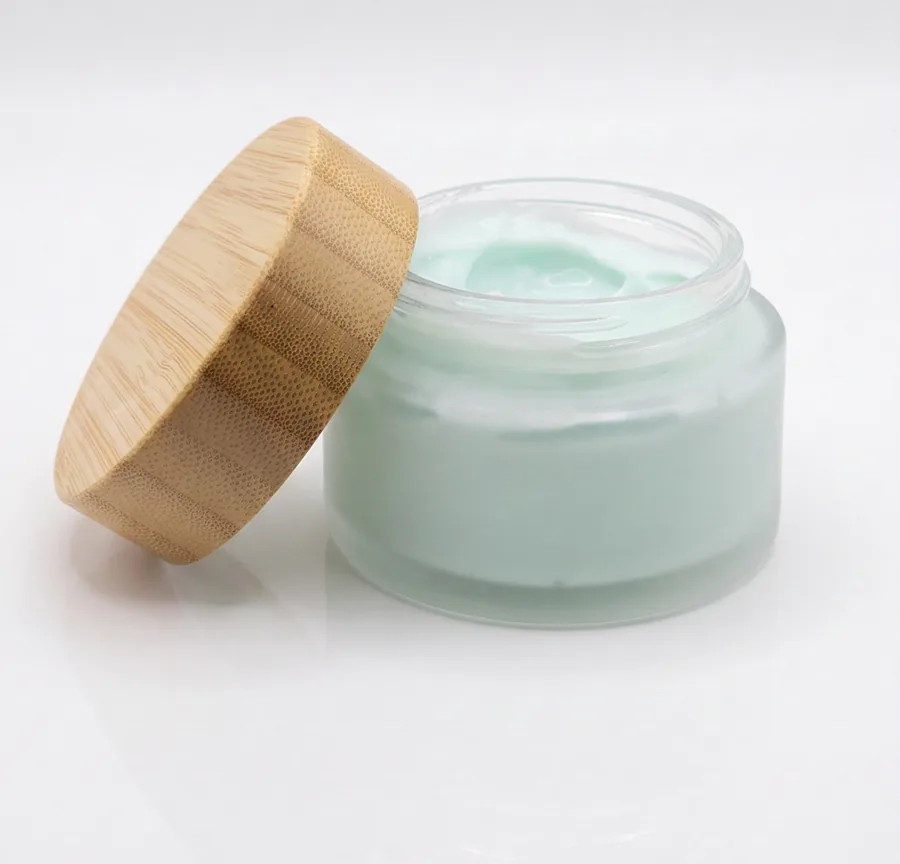 AuraAnn jar with the bamboo lid leaning against it, cream visible inside